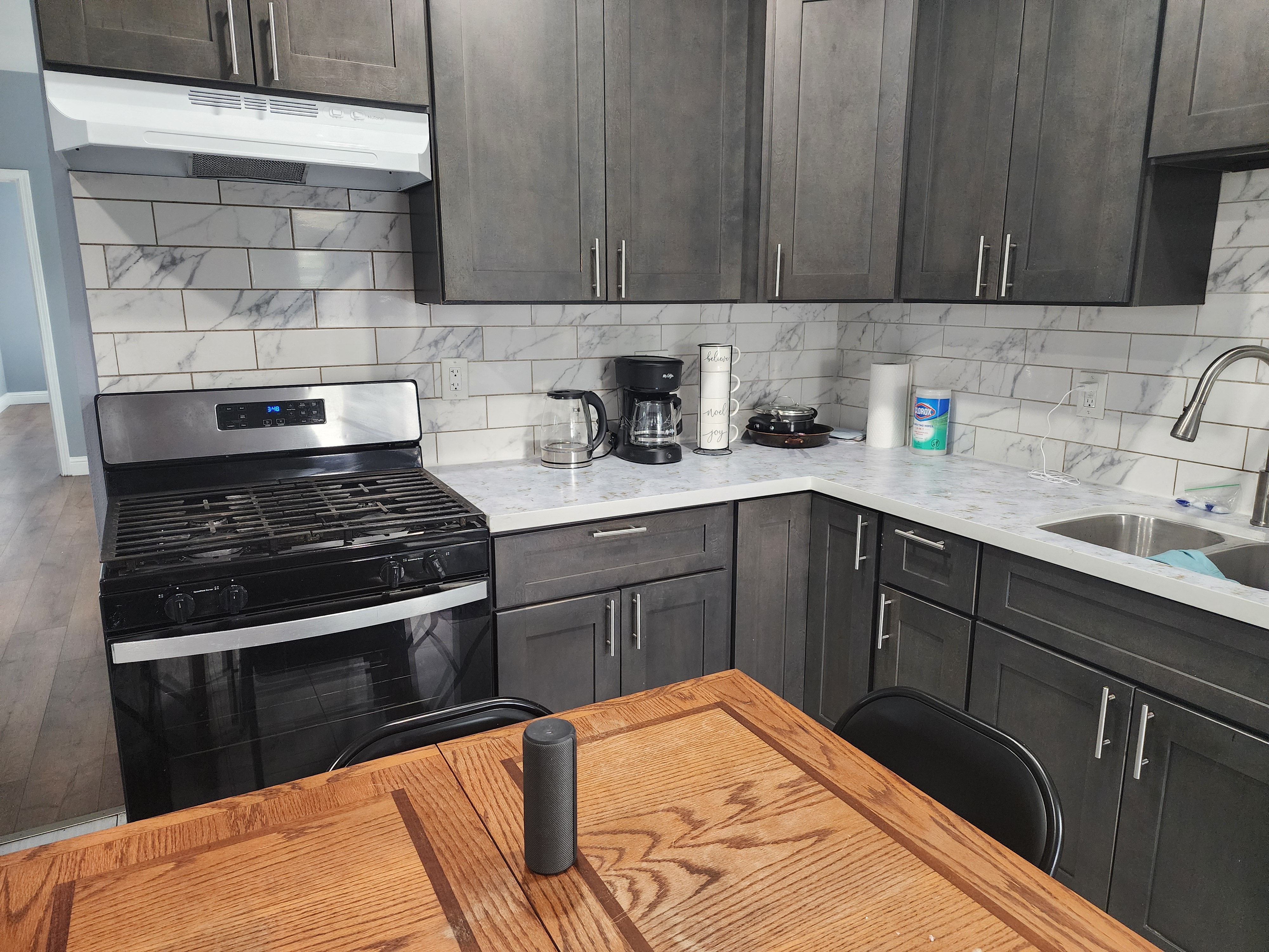Updated kitchen with dark cabinetry, tiled backsplash, and gas range
