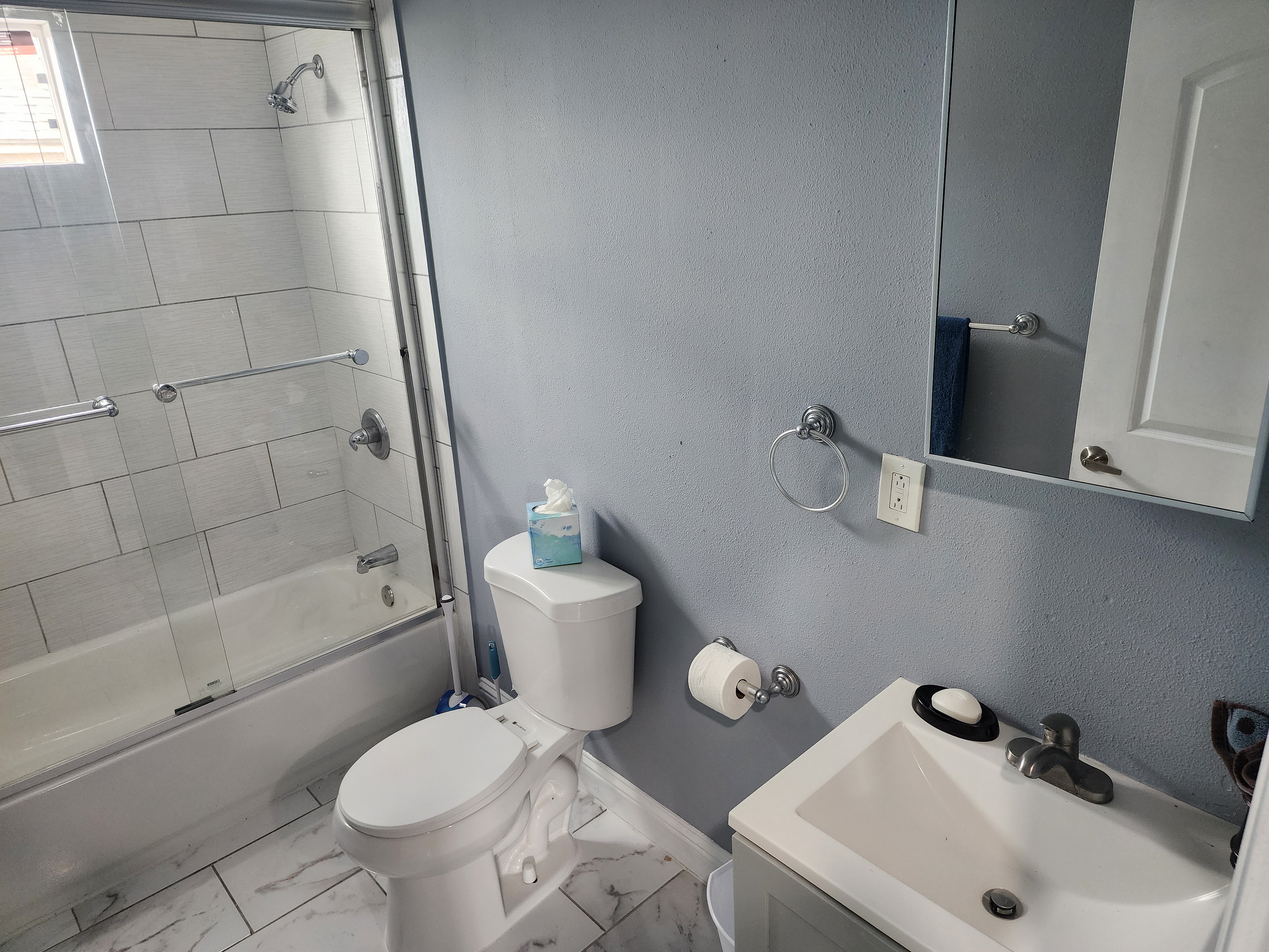 Clean bathroom with sink, toilet, mirror, and tiled shower